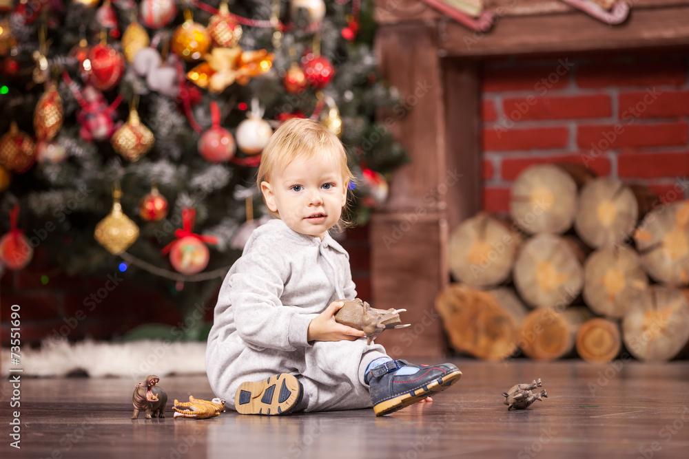 Little boy playing with toy animals by Christmas tree Little boy playing with toy animals by Christmas tree