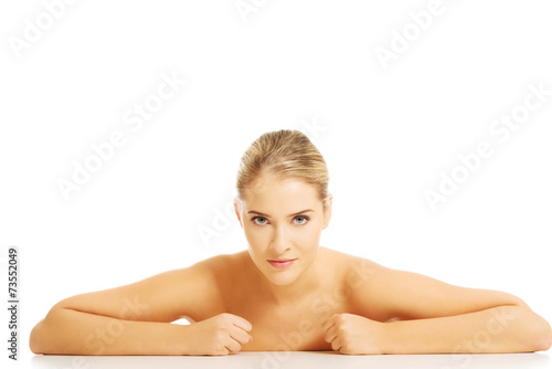 Portrait of angry nude woman sitting at the desk making fists