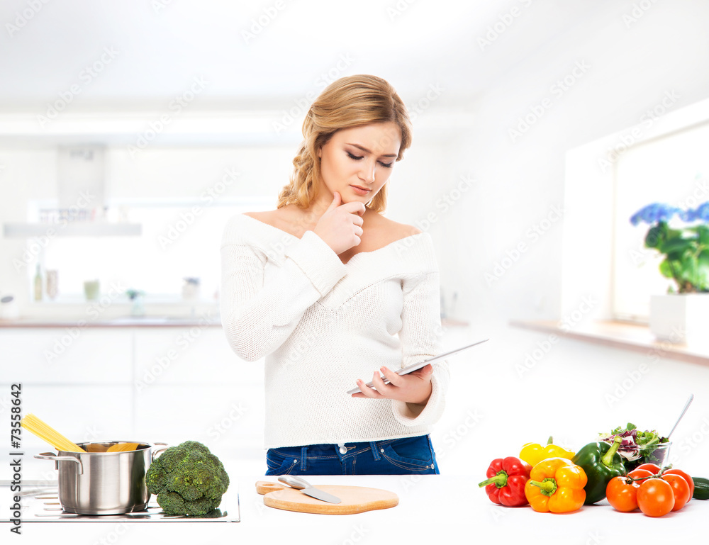 Young and beautiful housewife woman cooking in a kitchen
