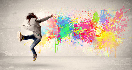 Happy teenager jumping with colorful ink splatter on urban backg