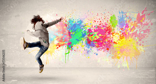 Fototapeta Naklejka Na Ścianę i Meble -  Happy teenager jumping with colorful ink splatter on urban backg