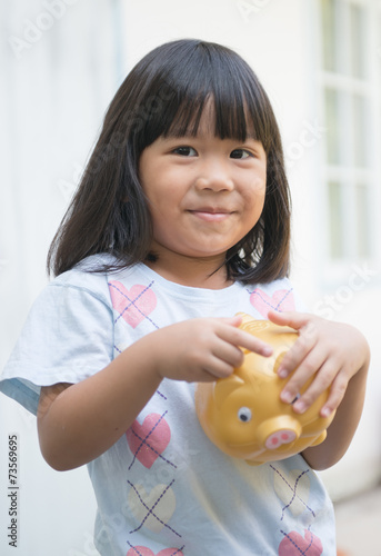 little girl saving money in a piggybank