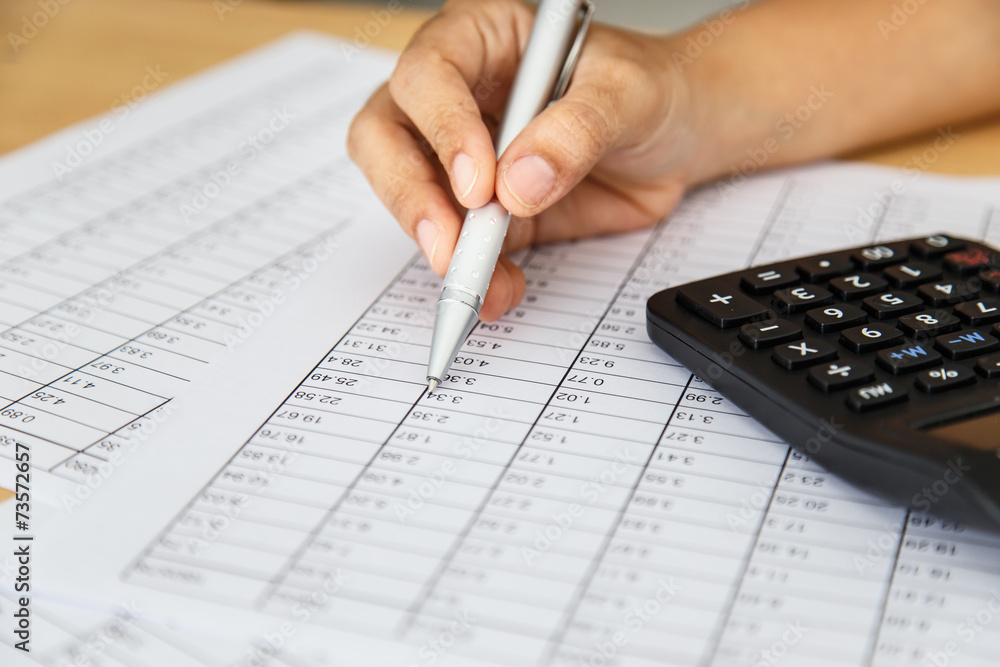 Close up woman hand holding pen on spreadsheet Close up woman hand holding pen on spreadsheet
