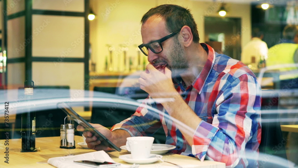Man eating lunch and using tablet in the restaurant, steadycam Man eating lunch and using tablet in the restaurant, steadycam