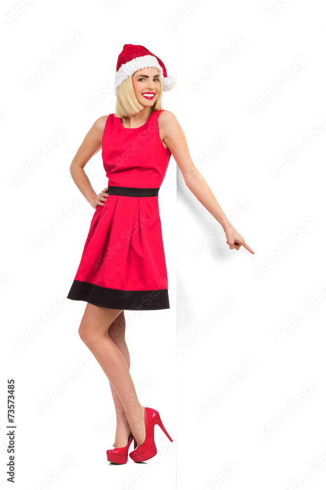 Relaxed Blonde Santa Girl leaning on the wall and pointing Relaxed Blonde Santa Girl leaning on the wall and pointing