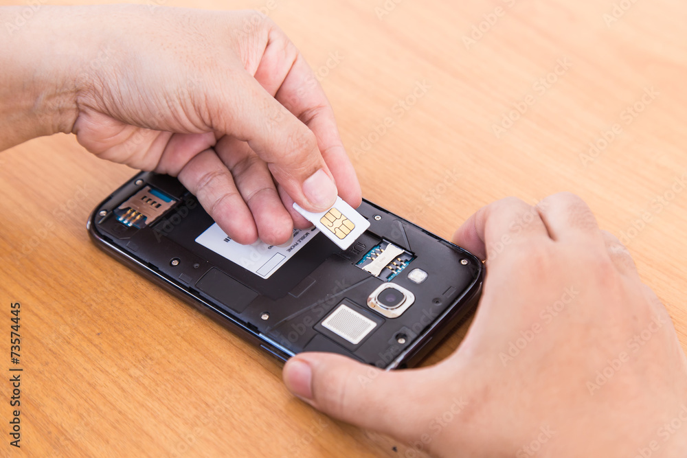 hand holding SIm card and smartphone on wood background hand holding SIm card and smartphone on wood background