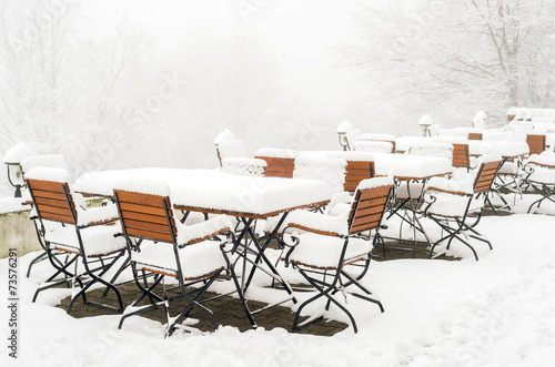 Tables and chairs covered in fresh snow