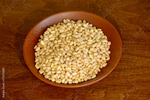 Cedar pine nuts in a ceramic plate on a wooden background