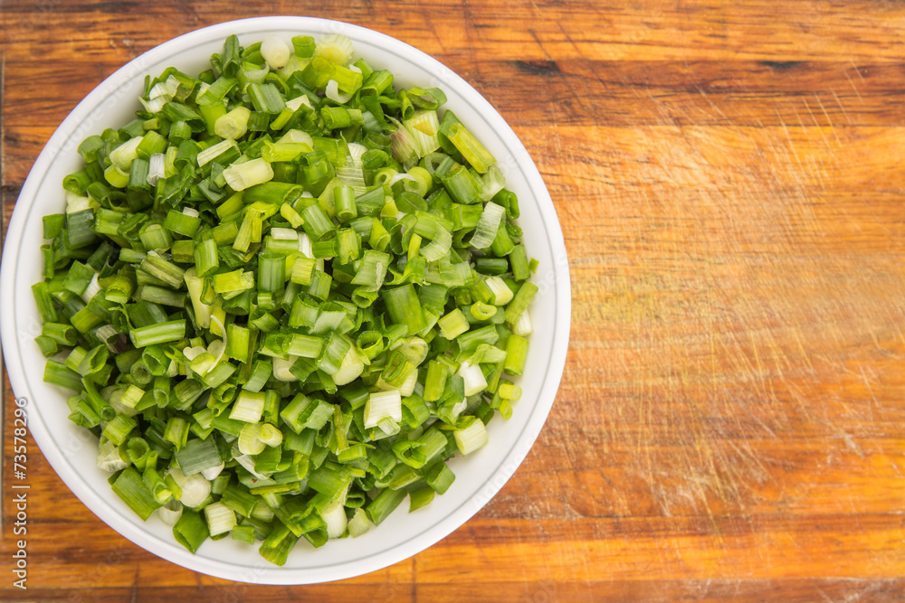 Chopped scallion or spring onion leaves in a white bowl Chopped scallion or spring onion leaves in a white bowl