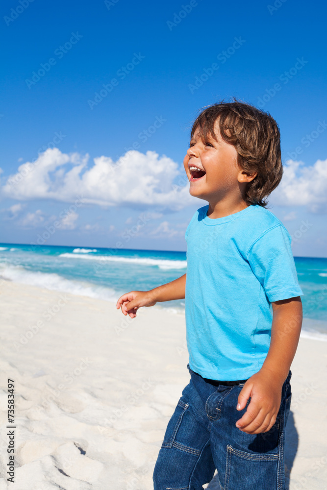 Laughing boy standing on the sandy beach Laughing boy standing on the sandy beach