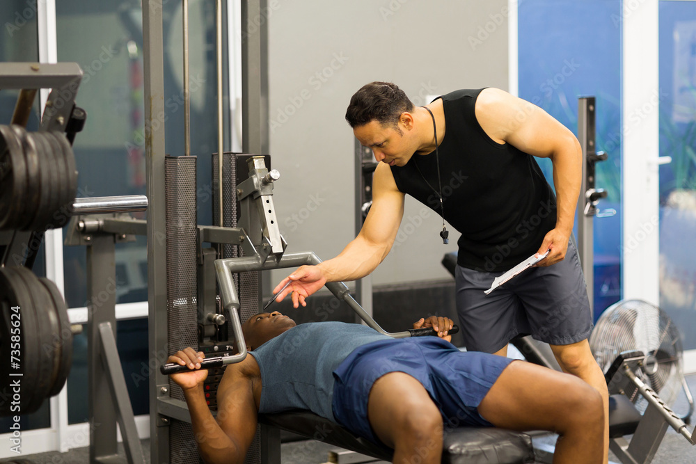 african man in gym with personal fitness trainer african man in gym with personal fitness trainer