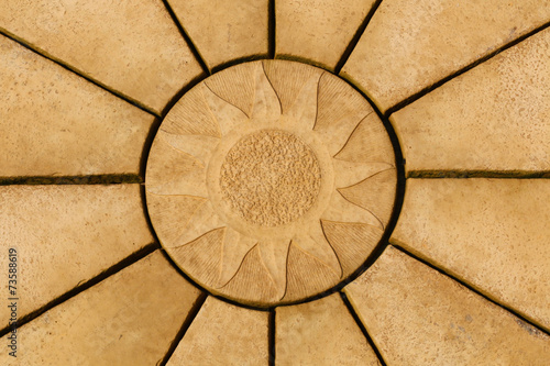 Sun design on golden coloured paving stone star pattern.  Backgr