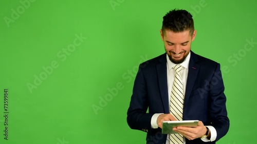 business man works on tablet and smiles - green screen - studio