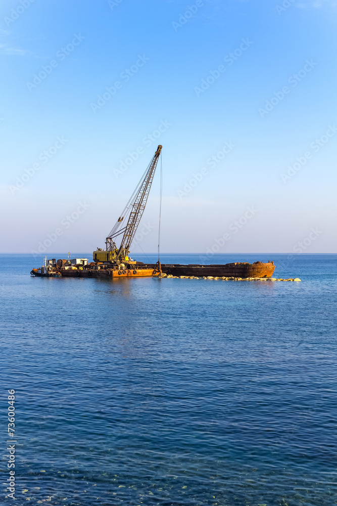 The Elevating Crane Unloads Stones from the Barge at Sea. The Elevating Crane Unloads Stones from the Barge at Sea.