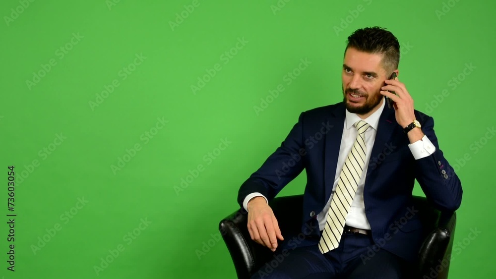 business man sits and phone and smiles - green screen business man sits and phone and smiles - green screen