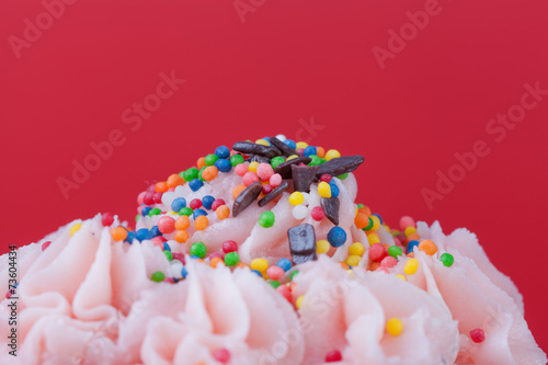 Cupcake with pink cream on a red background close up