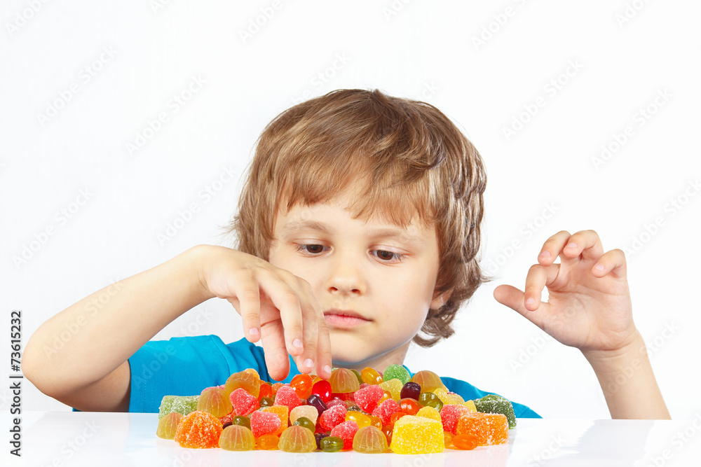 Little blonde child with jelly candies on a white background Little blonde child with jelly candies on a white background