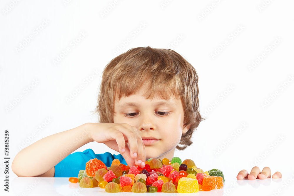 Little blonde child with candies on a white background Little blonde child with candies on a white background