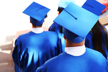 Graduate students wearing graduation hat and gown, outdoors