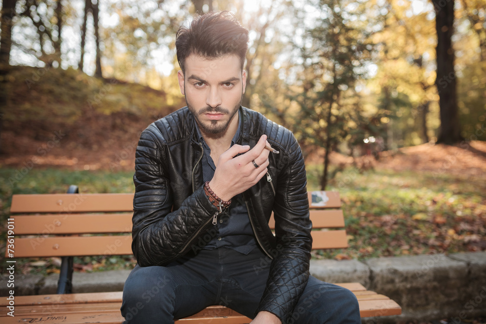 Fashion man sitting on a bench in the park Fashion man sitting on a bench in the park