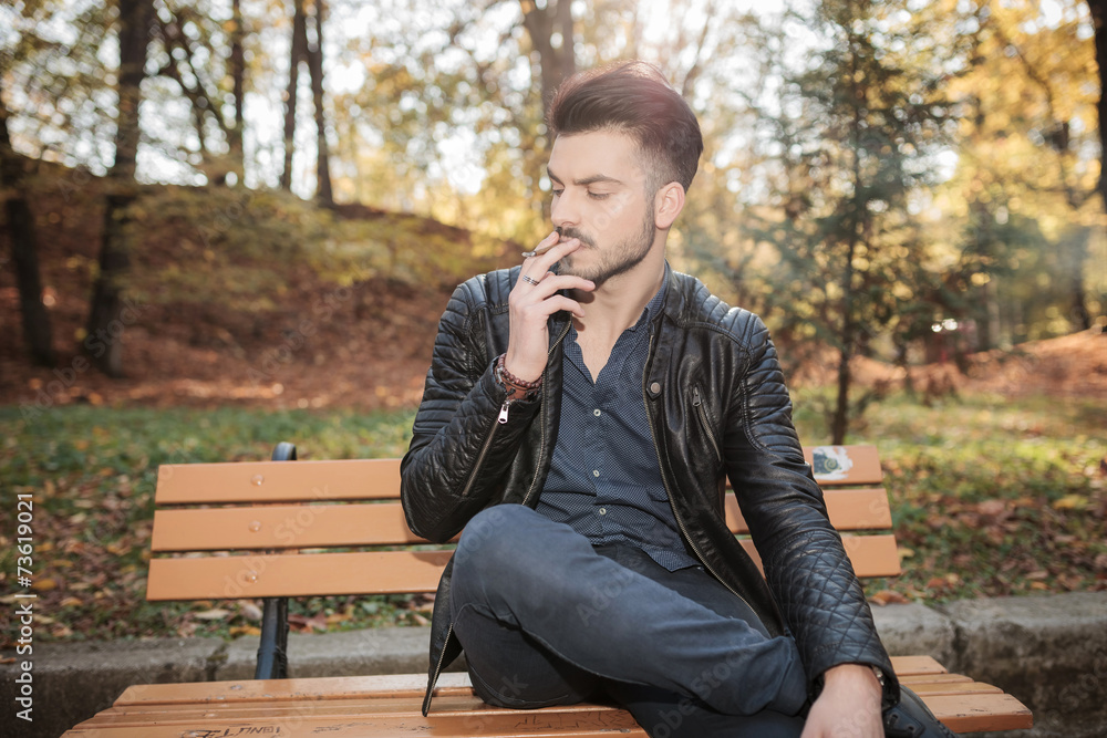 fashion man sitting on a bench in the park fashion man sitting on a bench in the park