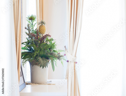 Artificial flowers bouquet on window sill frame with curtains
