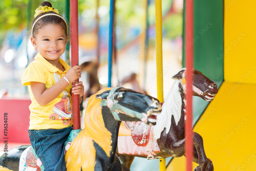 Fototapeta premium Cute mixed race girl riding a carousel