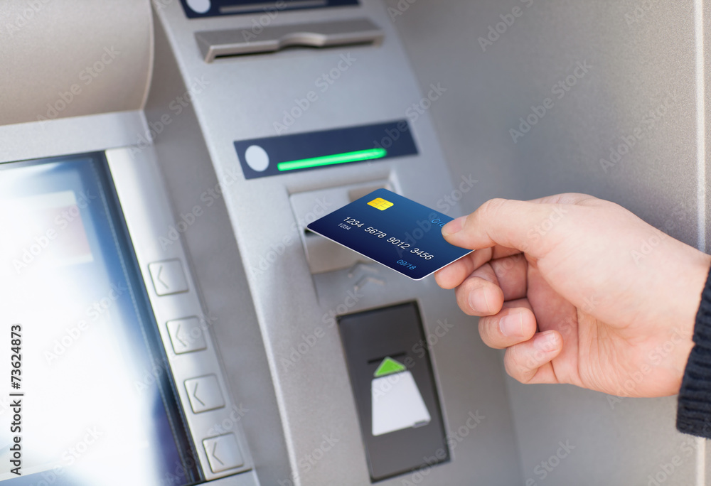 man puts credit card into ATM man puts credit card into ATM