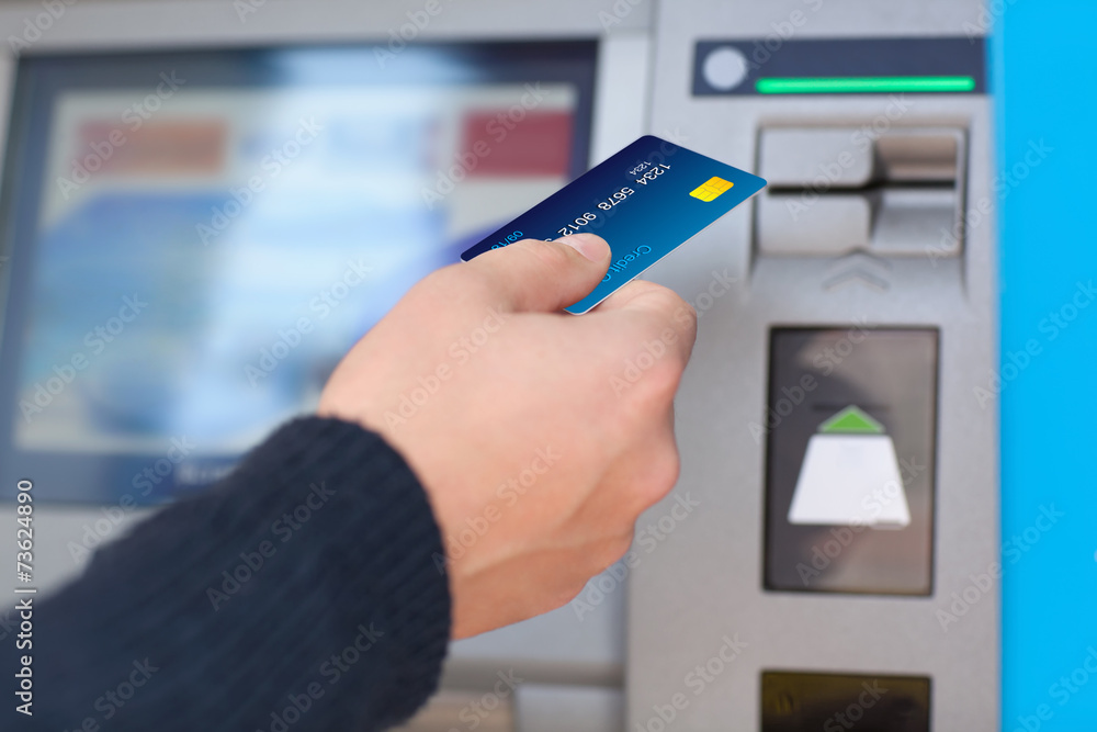 man puts credit card into ATM