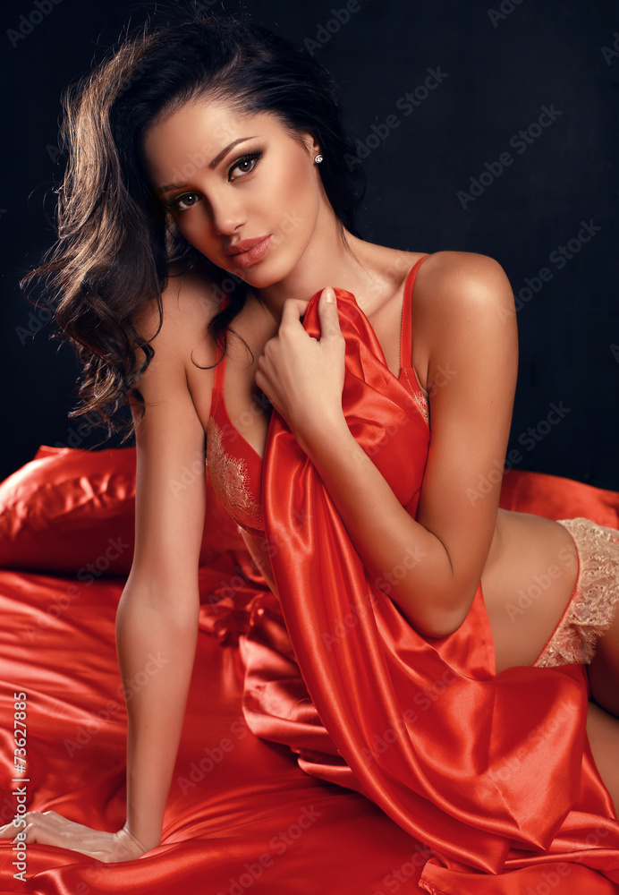 sexy woman with dark hair in red lingerie lying on silk sheet foto de Stock  | Adobe Stock