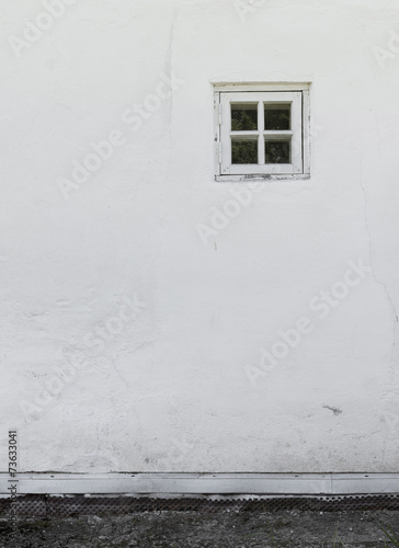 The old white plastered wall with a small window and a stone pat © lenatru