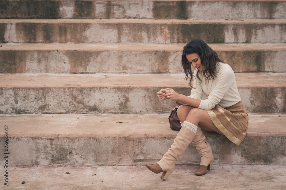 Beautiful young woman sitting on concrete steps