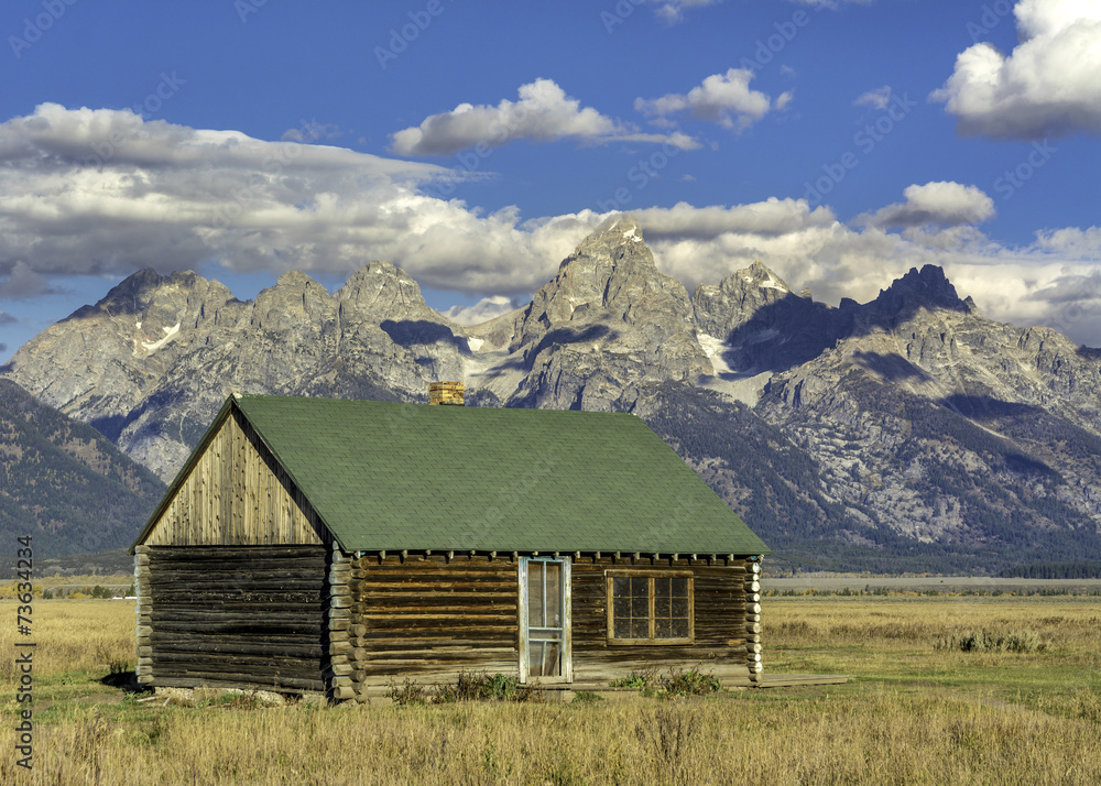 Tetons backdrop and rustic log cabin