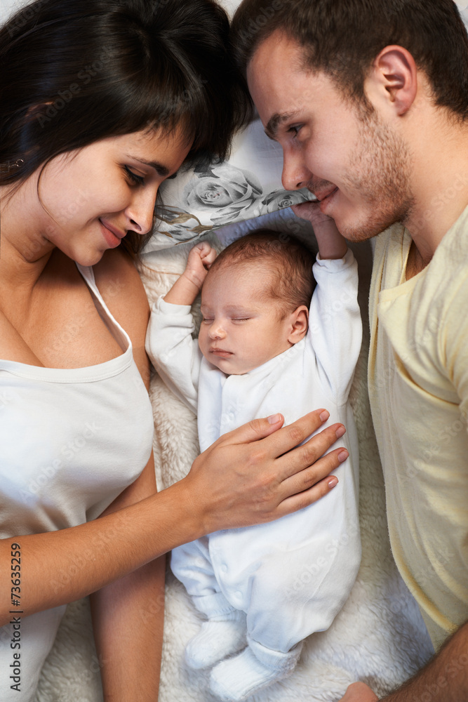 newborn lies between loving father and mother