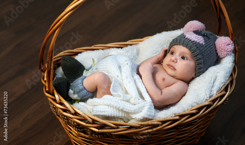newborn baby in  cap  basket on  floor