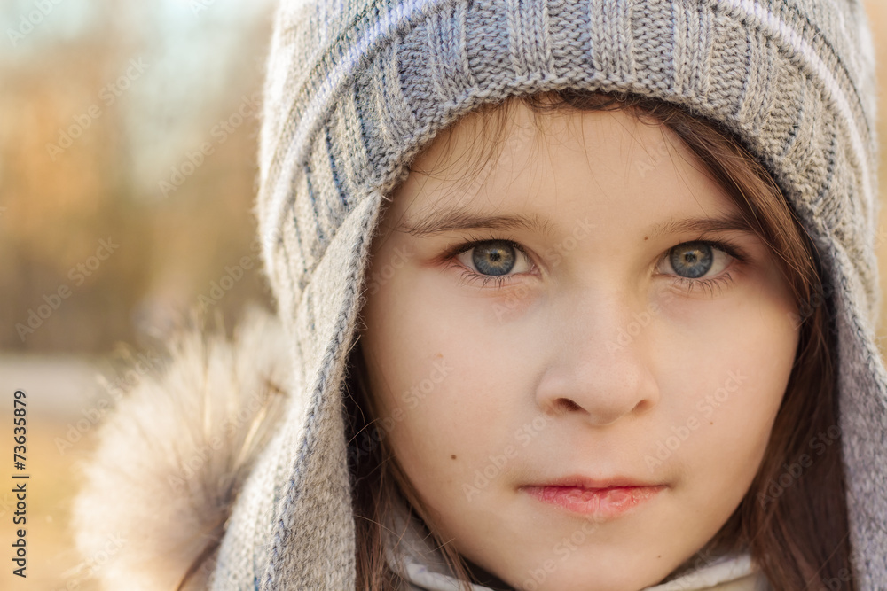 Close-up portrait of a pretty girl with blue eyes in gray knit h Close-up portrait of a pretty girl with blue eyes in gray knit h