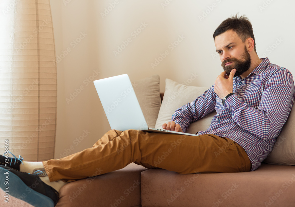 Young bearded man working on laptop at home Young bearded man working on laptop at home