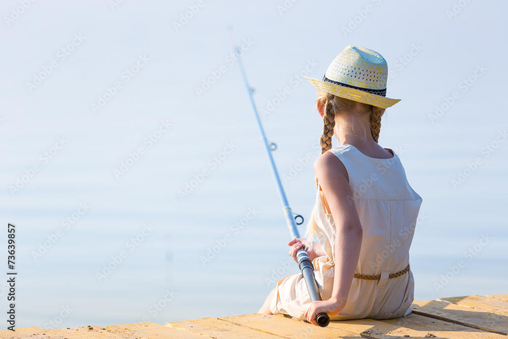 Girl in a dress and a hat with a fishing rod Girl in a dress and a hat with a fishing rod