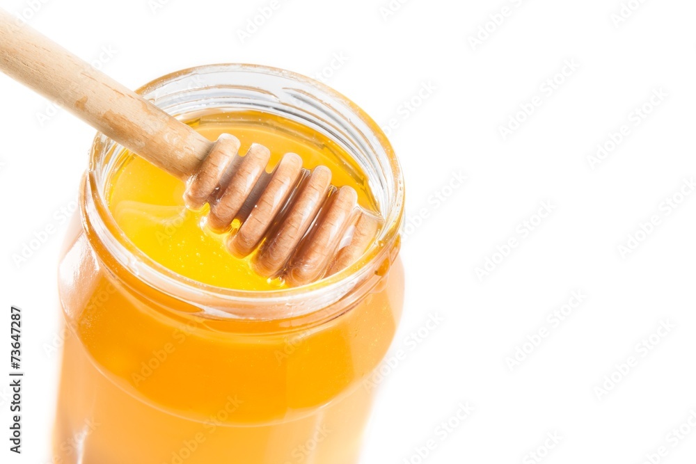 honey jar on white background with wooden honey dipper inside honey jar on white background with wooden honey dipper inside