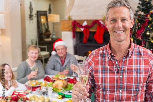 Smiling father toasting at camera in front of his family