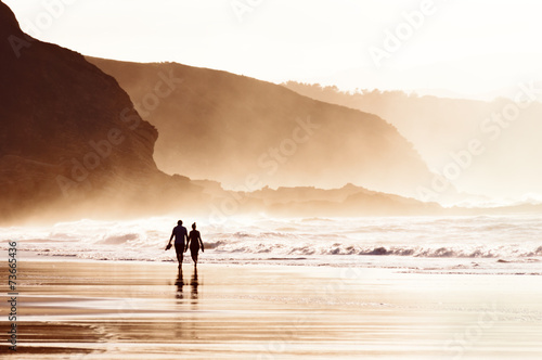 couple walking on beach with fog