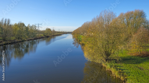 Trees along a canal under sunny sky in autumn © Naj