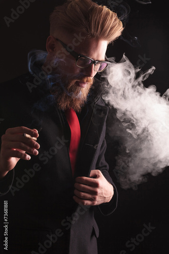 fashion man pulling his coat while smoking