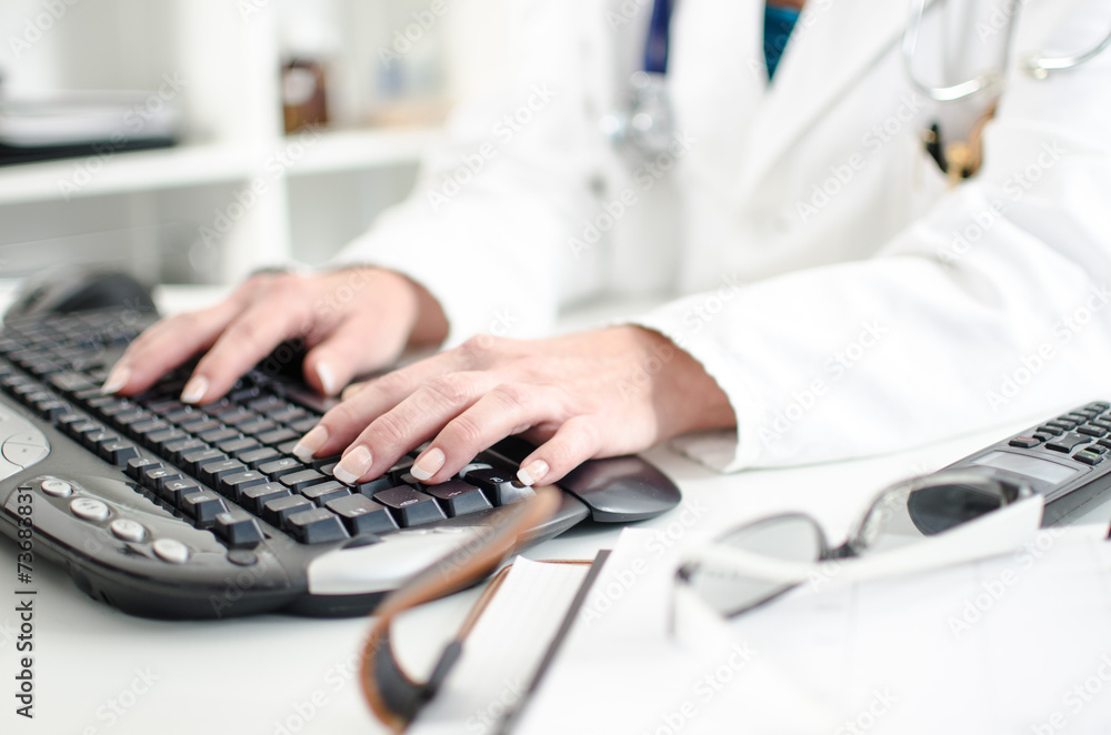Female doctor taping on a computer keyboard Female doctor taping on a computer keyboard