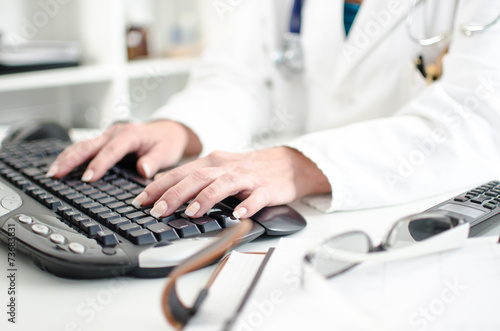 Obraz na plátně Female doctor taping on a computer keyboard
