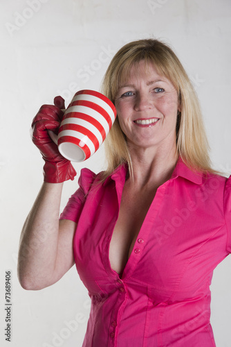 Woman in pink shirt holding a hot drink in a mug