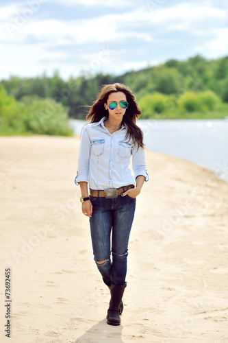 Full length portrait of stylish woman walking on a beach