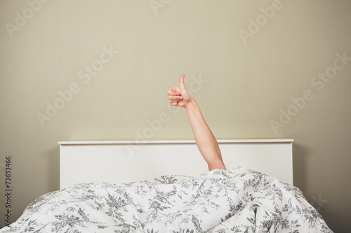 Woman in bed giving thumbs up photo
