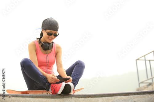 woman skateboarder listening music from cellphone mp3 player on 