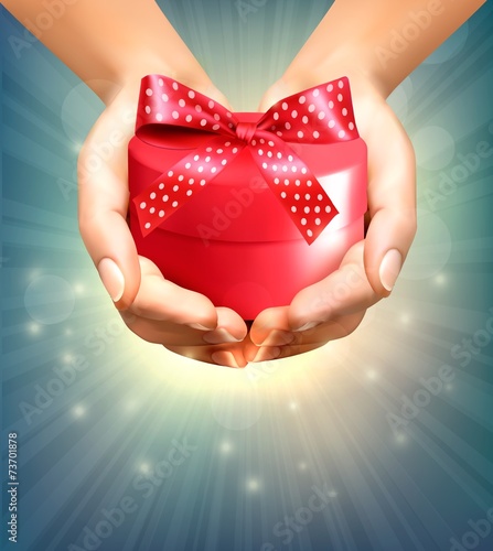 Holiday background with hands holding gift box. Concept of givin